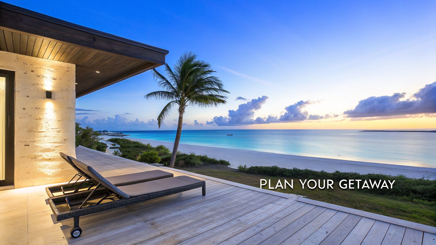 A luxurious beach house balcony with lounge chairs overlooking a serene white sand beach and turquoise ocean at sunset.