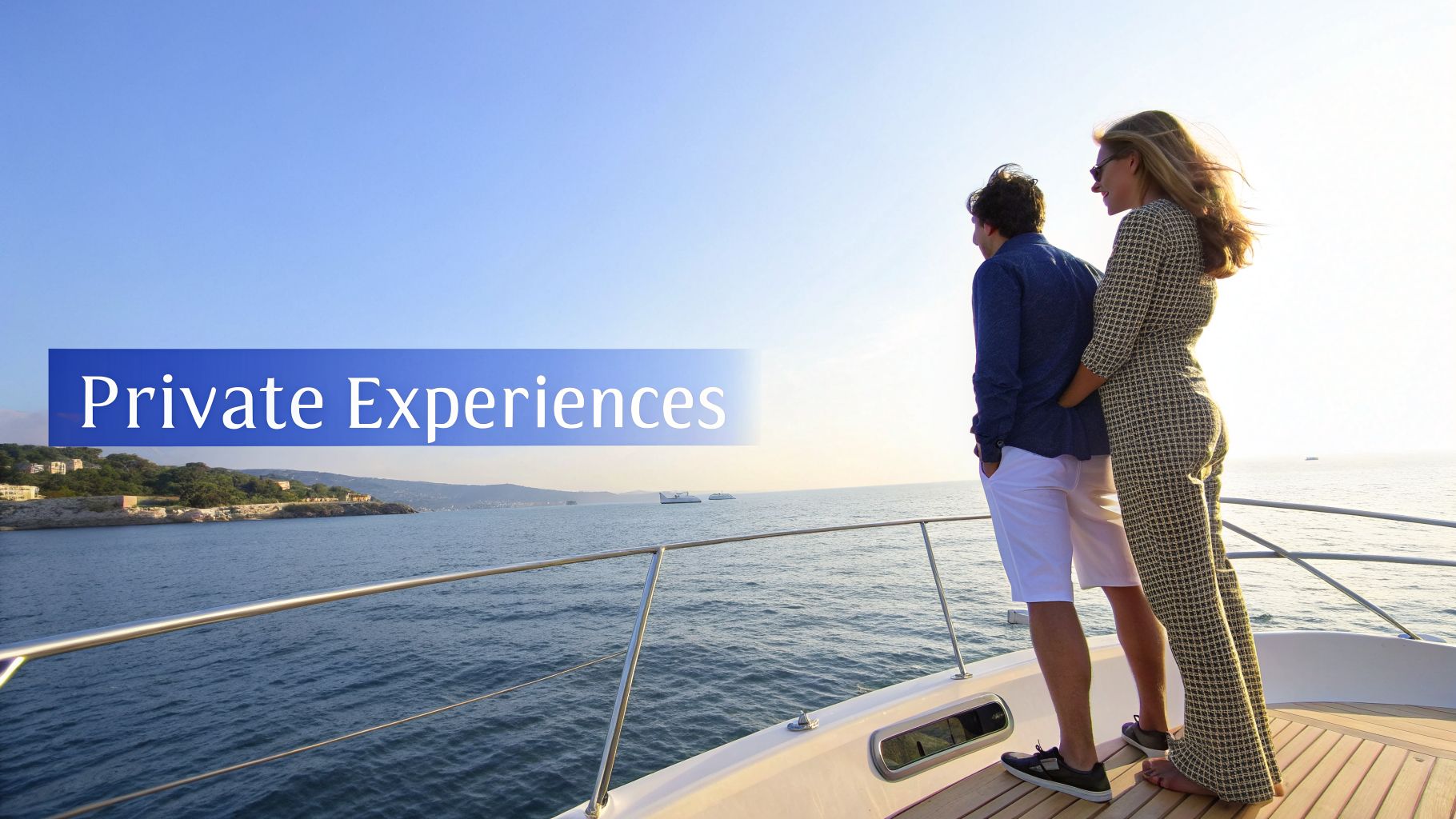 A couple on a yacht enjoys a private experience, gazing at the sea and distant coastline.