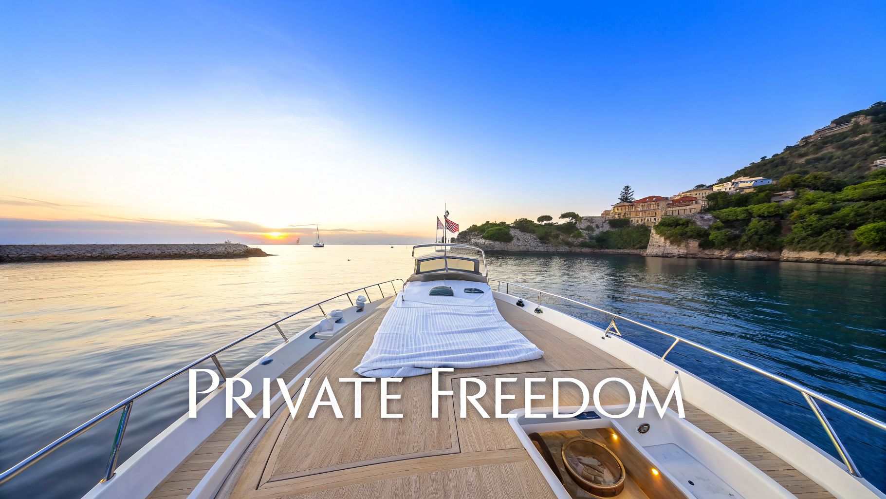 A luxury yacht sailing into a tranquil Mediterranean harbor at sunset, with a coastal town and hills in the background.