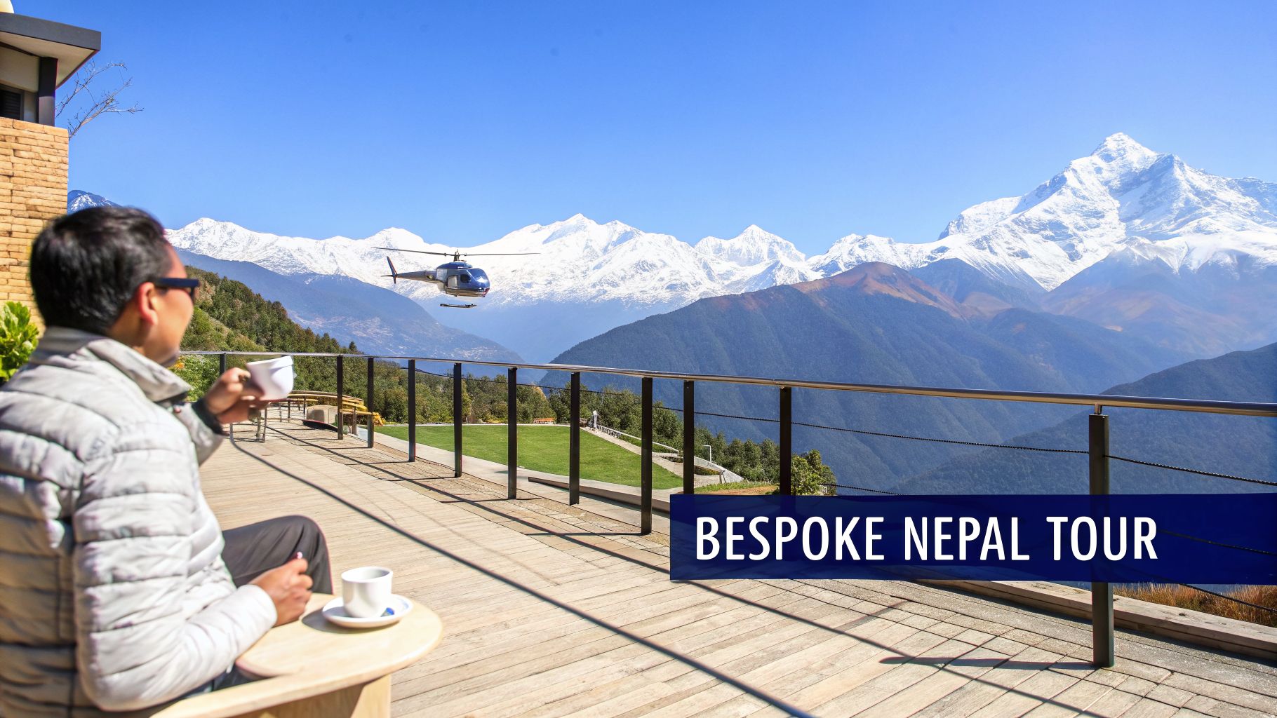 Man enjoying a scenic mountain view with a helicopter in Nepal, holding a cup on a sunny day.