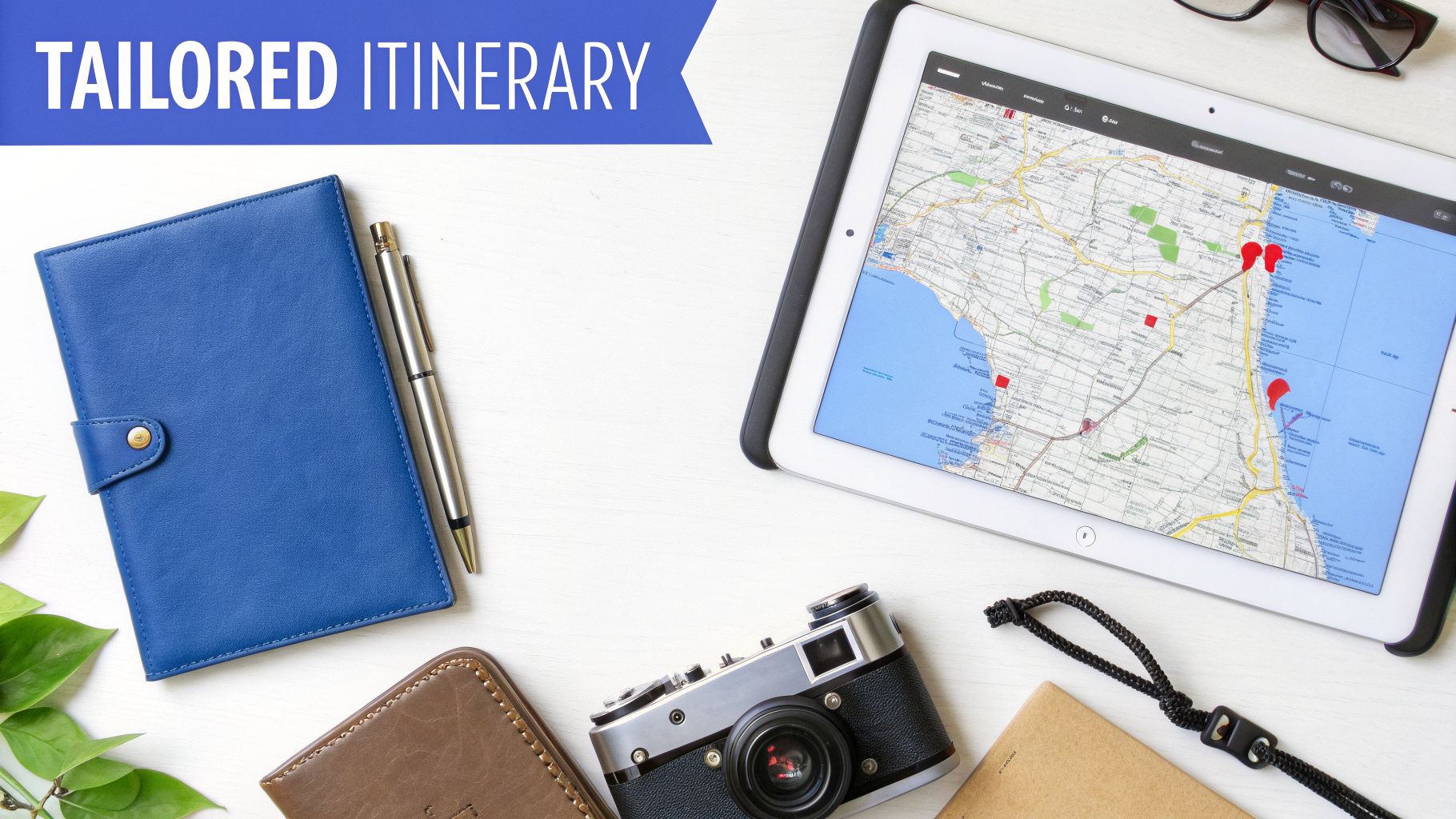 Travel planning flat lay featuring a map on a tablet, notebook, pen, camera, and "TAILORED ITINERARY" text.