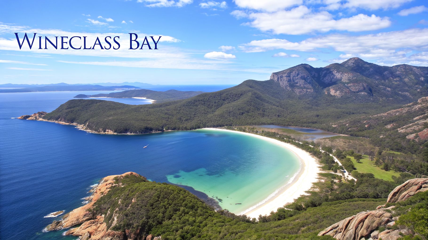Aerial view of Wineglass Bay in Tasmania with turquoise water, white sand beach, and green mountains.