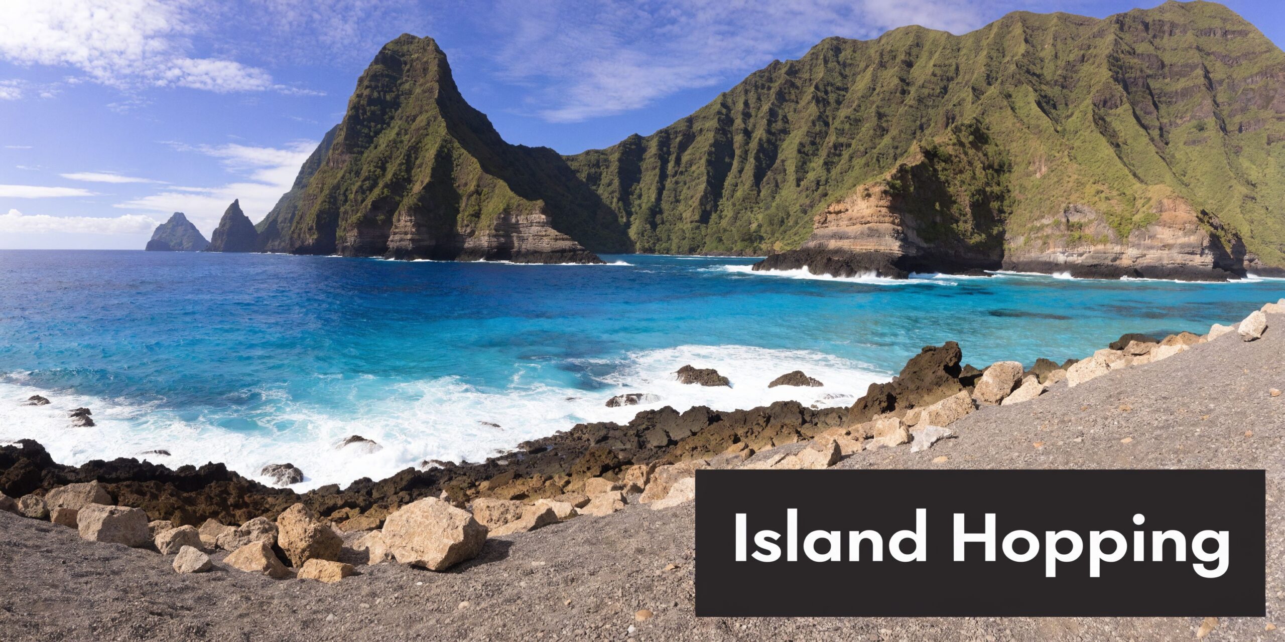 A scenic view of a tropical volcanic island coastline with clear blue water and rocky shores.