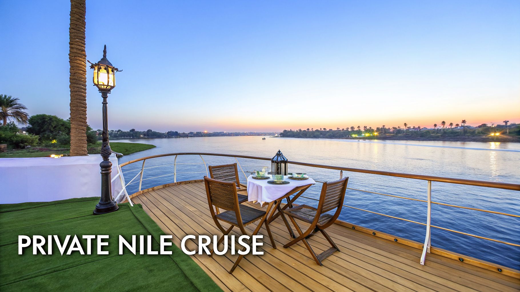 Private deck on a luxury Nile cruise ship at sunset, with a set table and river views.