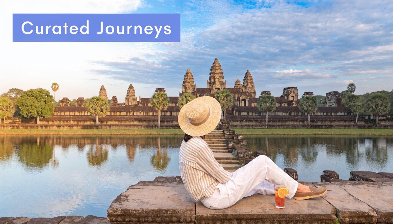 A woman wearing a straw hat sits overlooking the ancient temple of Angkor Wat in Cambodia.