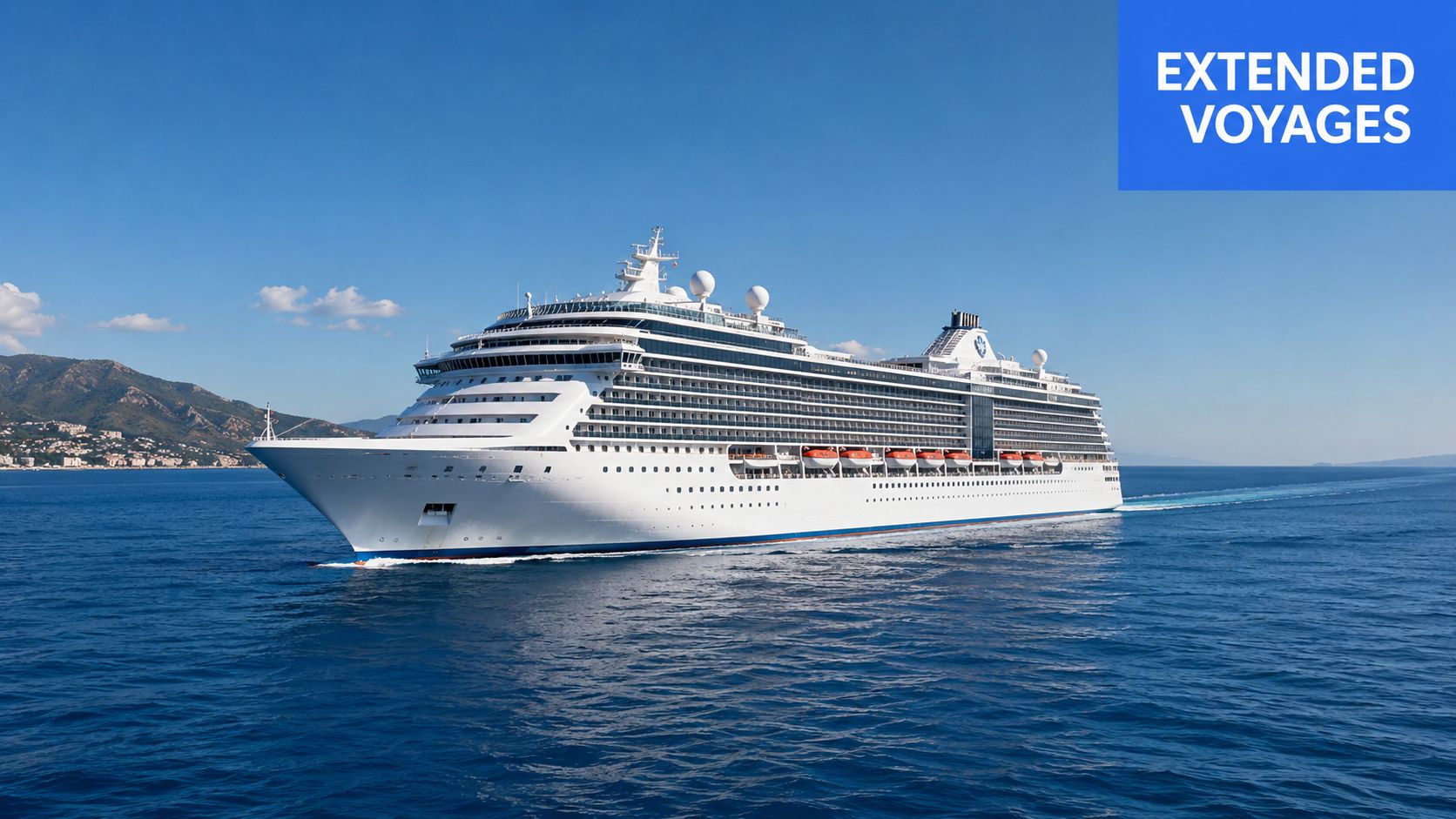 A large white luxury cruise ship sailing across calm blue waters near a coastal mountain range.