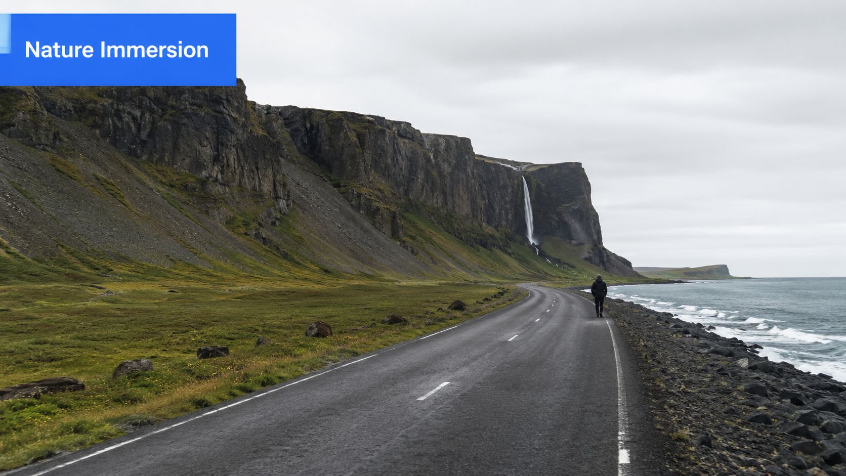 A lone traveler walking on a coastal road in Iceland beneath towering cliffs and a cascading waterfall.